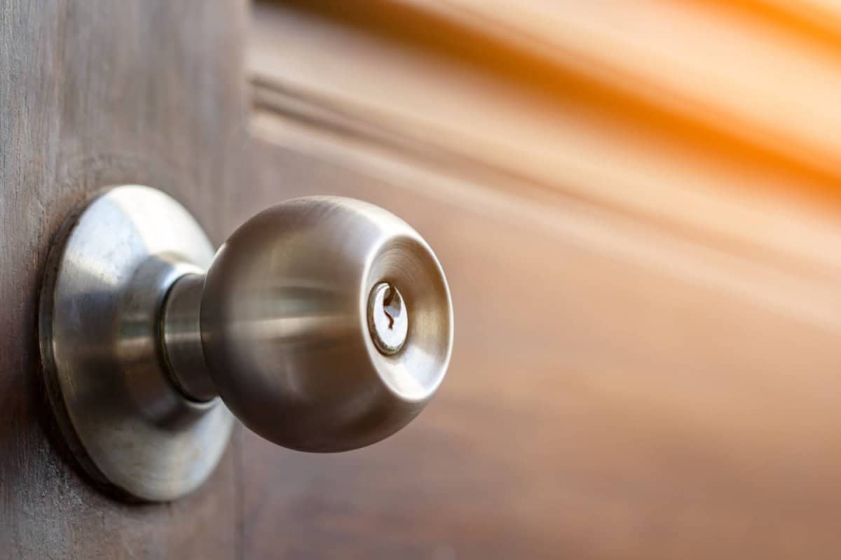stainless door knob and keyhole on old wooden door with sunlight effect, shallow depth of field